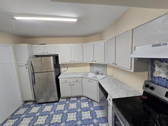 kitchen with decorative backsplash, exhaust hood, appliances with stainless steel finishes, white cabinetry, and sink