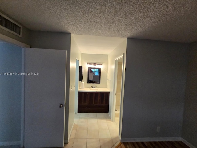 corridor featuring light tile patterned flooring, a textured ceiling, and sink