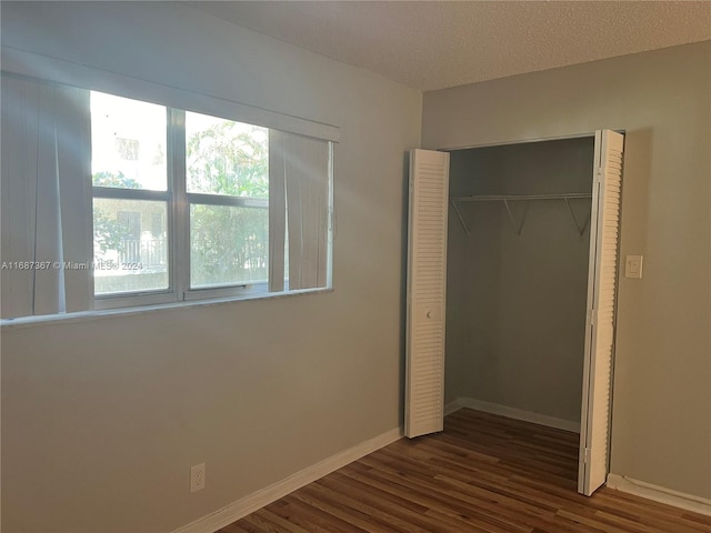 unfurnished bedroom featuring a closet, a textured ceiling, and dark hardwood / wood-style flooring