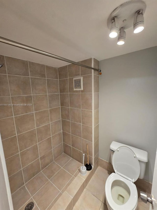 bathroom with tile patterned floors, a tile shower, and toilet