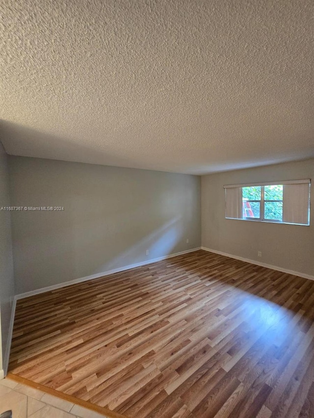 empty room with a textured ceiling and wood-type flooring