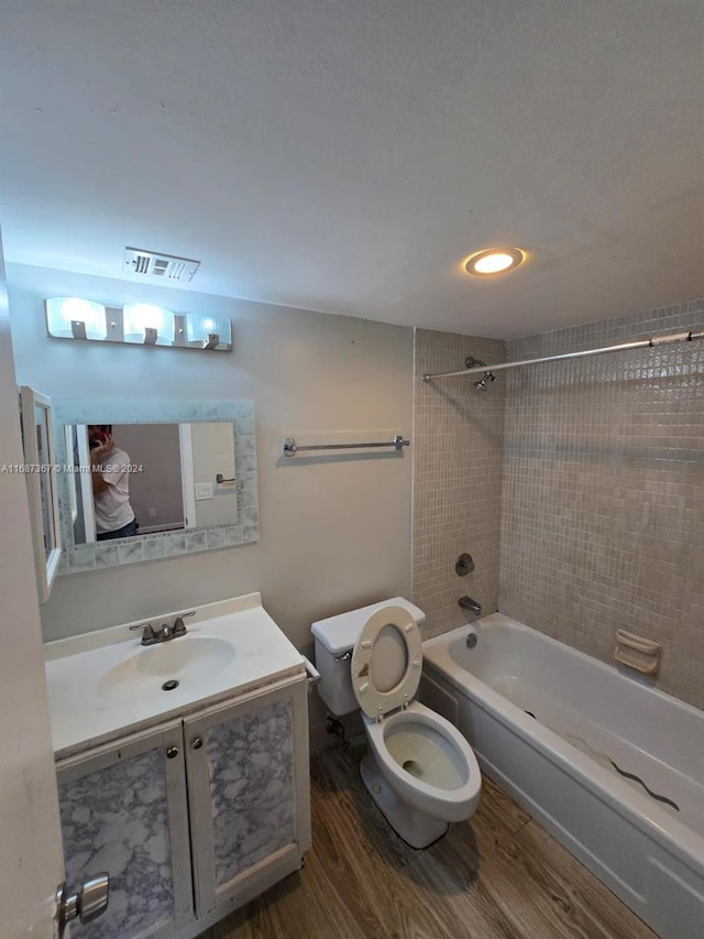 full bathroom featuring vanity, toilet, tiled shower / bath, and hardwood / wood-style floors