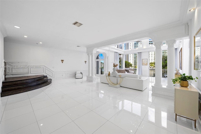 living area featuring visible vents, a decorative wall, ornamental molding, wainscoting, and ornate columns