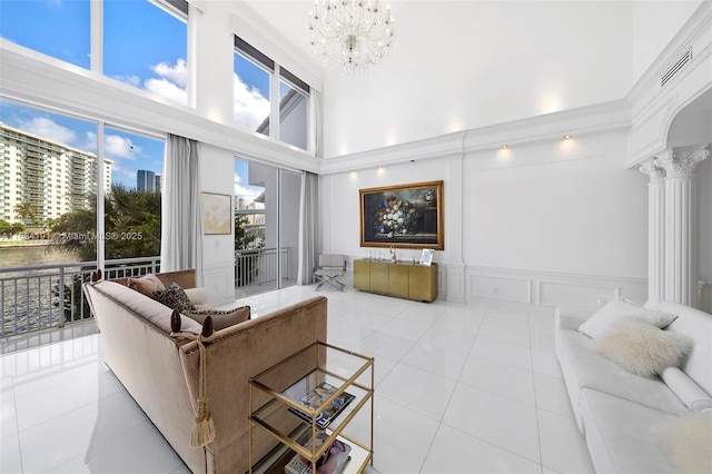 living room featuring a high ceiling, a decorative wall, ornate columns, and light tile patterned flooring