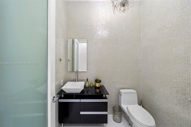 bathroom with tile walls, vanity, and toilet