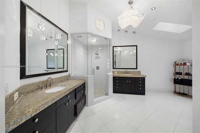 full bath with a stall shower, tile patterned flooring, two vanities, and a sink