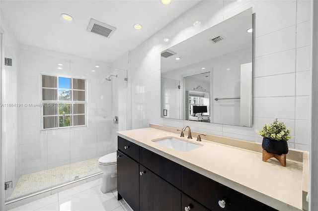 full bathroom with a stall shower, visible vents, toilet, vanity, and tile walls