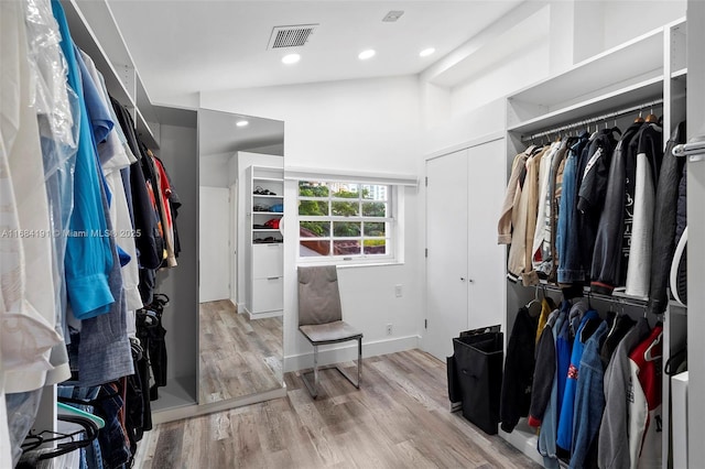 walk in closet with light wood-style floors, lofted ceiling, and visible vents