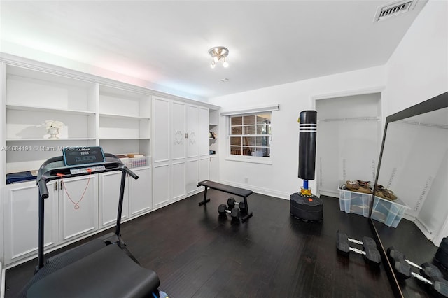 exercise room with visible vents, dark wood finished floors, and baseboards