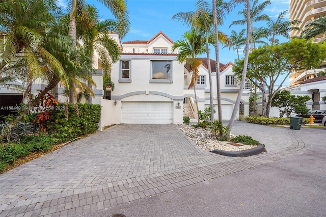 mediterranean / spanish home featuring a garage, decorative driveway, and stucco siding