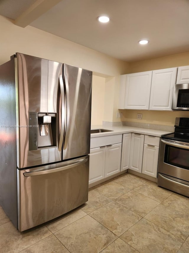 kitchen featuring beamed ceiling, sink, white cabinets, and stainless steel appliances