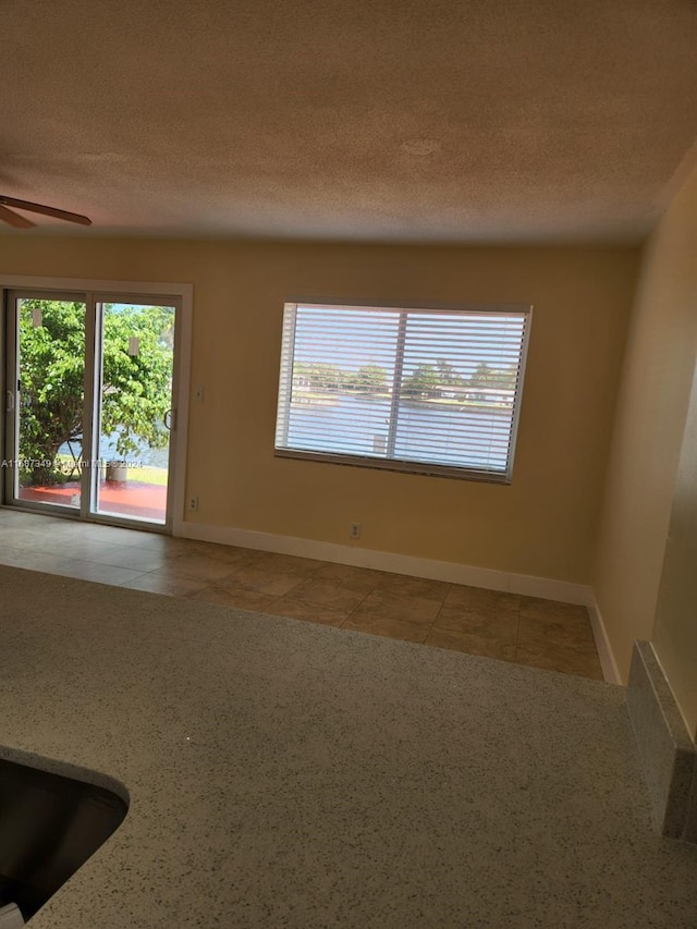 spare room with a textured ceiling, plenty of natural light, and ceiling fan