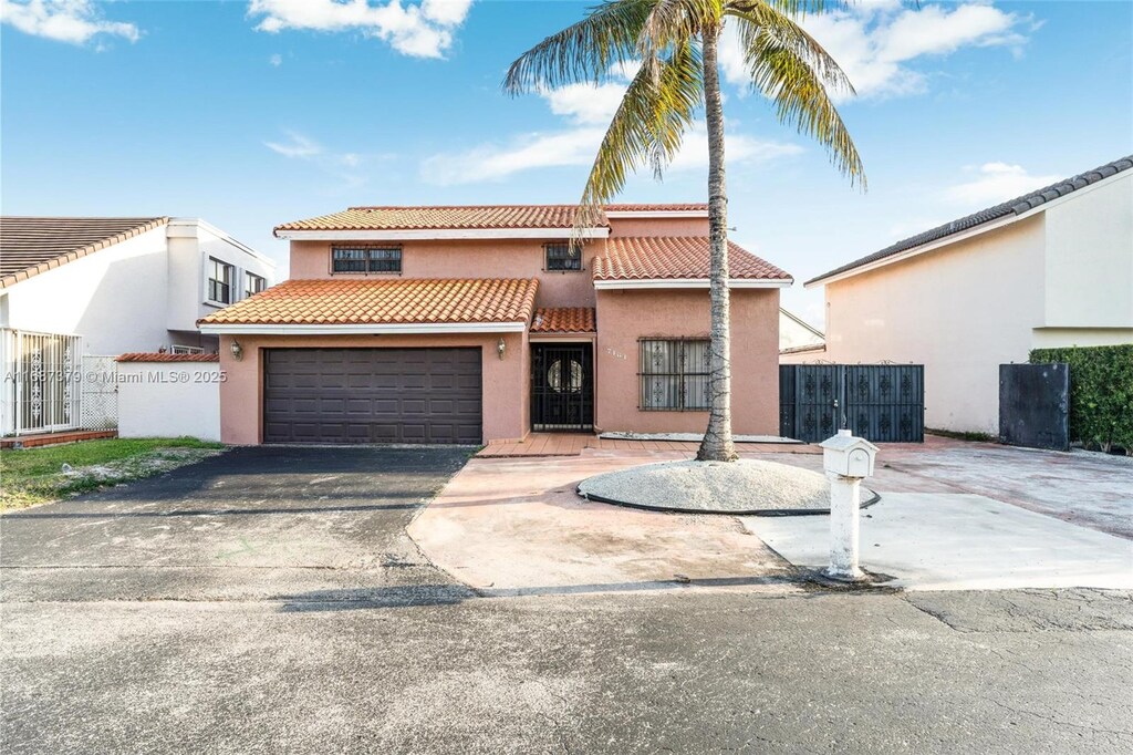 mediterranean / spanish-style house with a tiled roof, fence, driveway, and stucco siding
