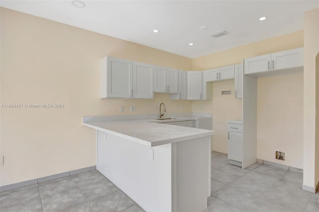 kitchen with white cabinetry, sink, kitchen peninsula, a kitchen breakfast bar, and light tile patterned floors