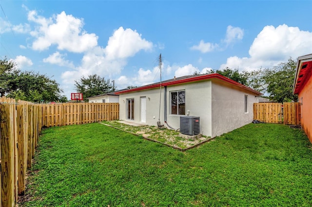 rear view of property with central AC unit and a lawn