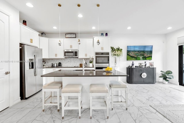 kitchen featuring dark countertops, tasteful backsplash, a kitchen breakfast bar, stainless steel appliances, and a sink