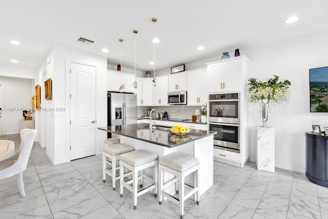 kitchen with white cabinetry, tasteful backsplash, appliances with stainless steel finishes, and a breakfast bar area