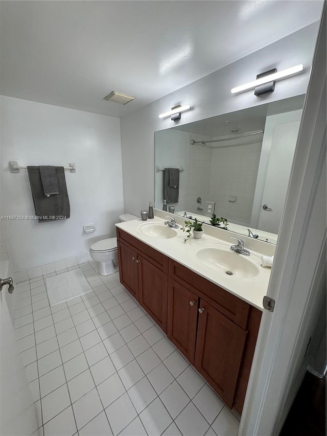 bathroom featuring vanity, toilet, tile patterned floors, and tiled shower