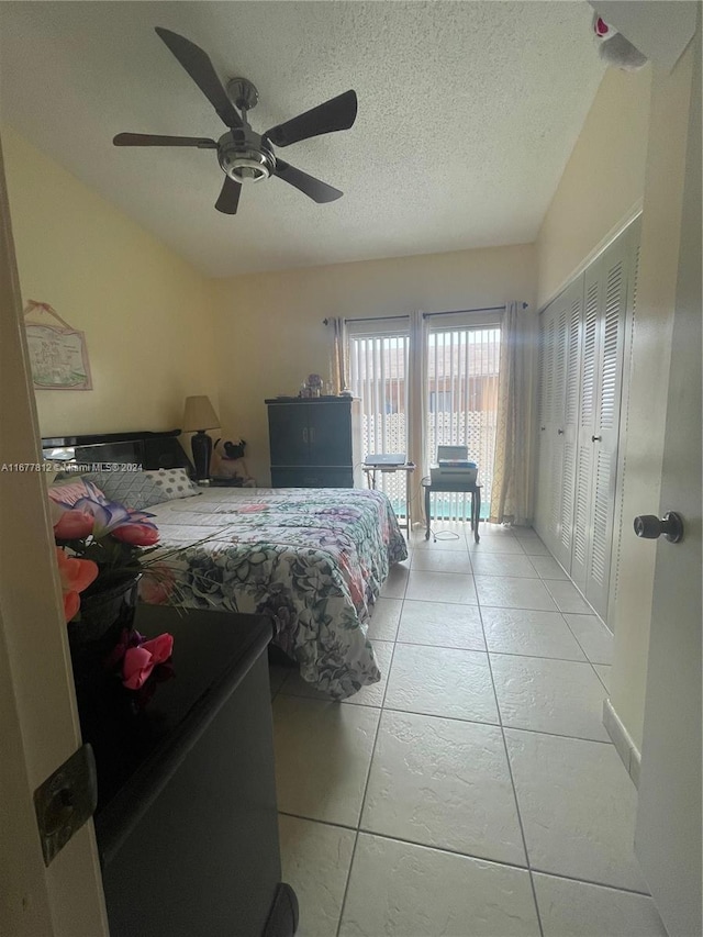 bedroom featuring a closet, a textured ceiling, light tile patterned flooring, and ceiling fan