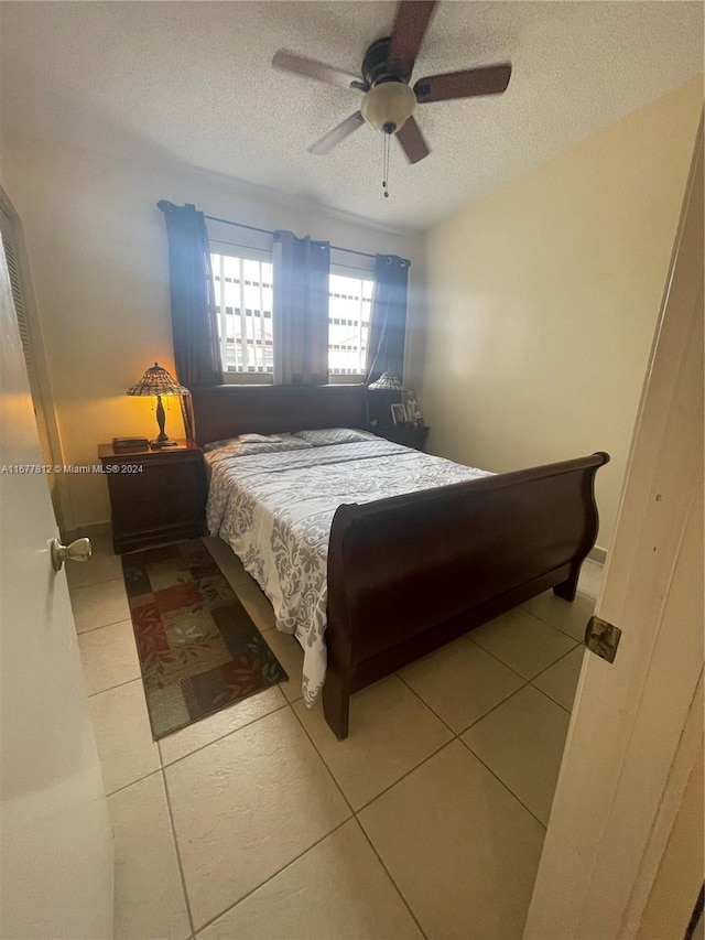 tiled bedroom with ceiling fan and a textured ceiling