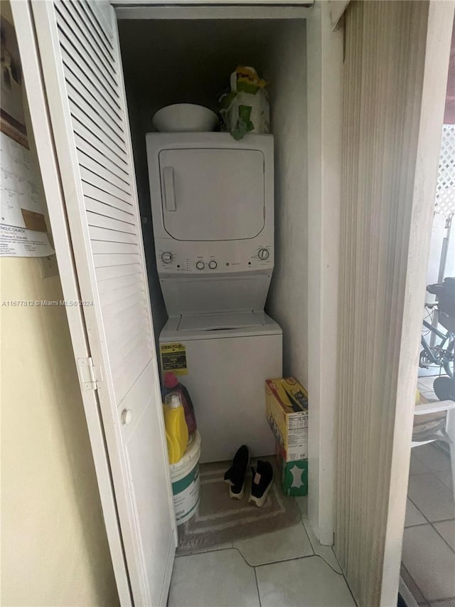 clothes washing area featuring stacked washer / drying machine and tile patterned flooring