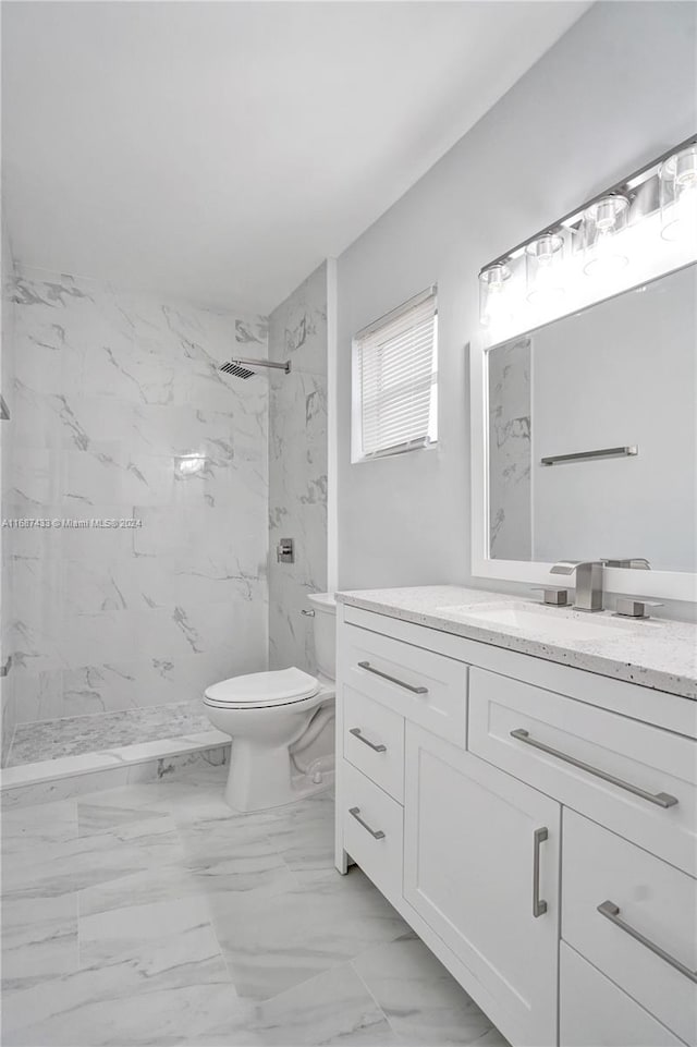 bathroom with toilet, vanity, and tiled shower