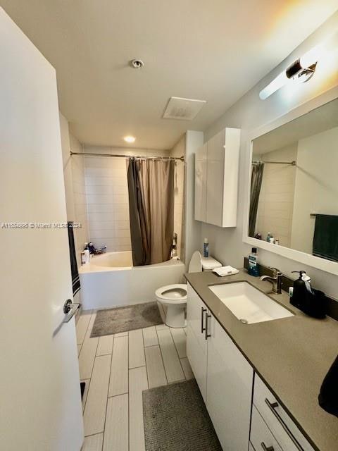 full bathroom featuring vanity, shower / bath combo with shower curtain, and toilet