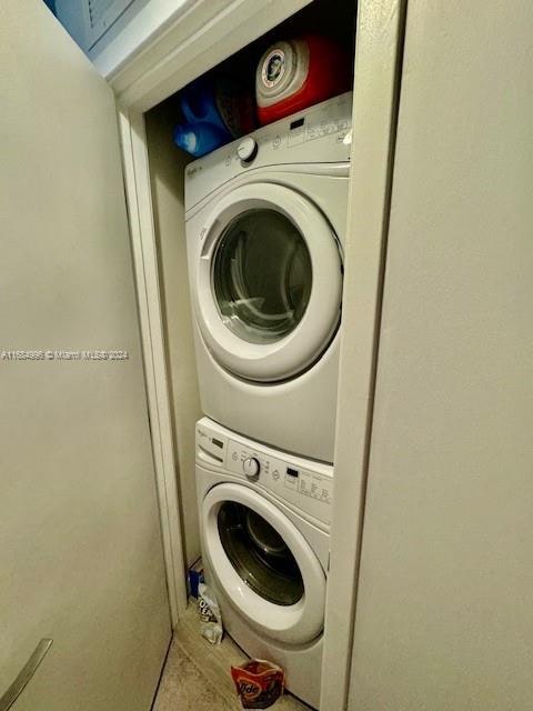 laundry area with stacked washer and clothes dryer and tile patterned floors