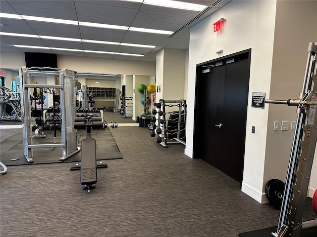 workout area featuring a drop ceiling and dark colored carpet