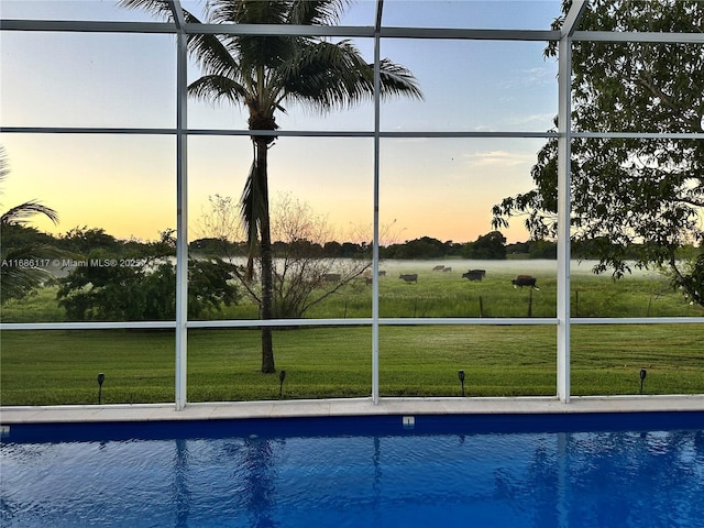 view of pool with glass enclosure and a yard