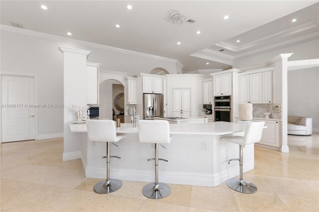 kitchen featuring a peninsula, appliances with stainless steel finishes, a breakfast bar, and backsplash