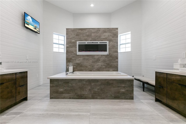 bathroom featuring a bath, vanity, and tile walls