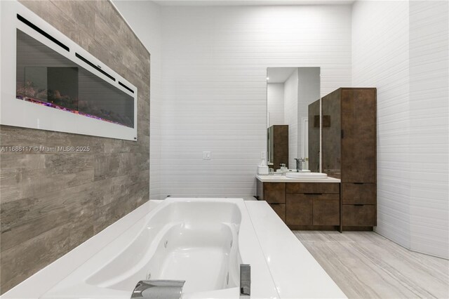 full bathroom with tile walls, a jetted tub, and vanity