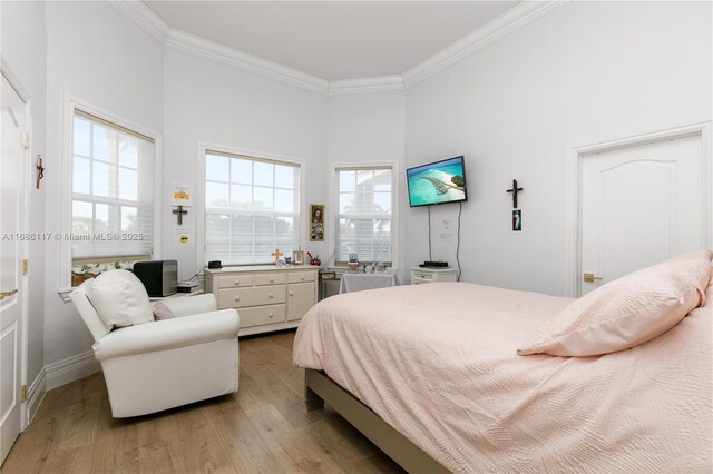 bedroom with ornamental molding, a towering ceiling, and light wood-style floors