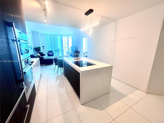 kitchen featuring hanging light fixtures, a center island with sink, light tile patterned floors, and black electric stovetop