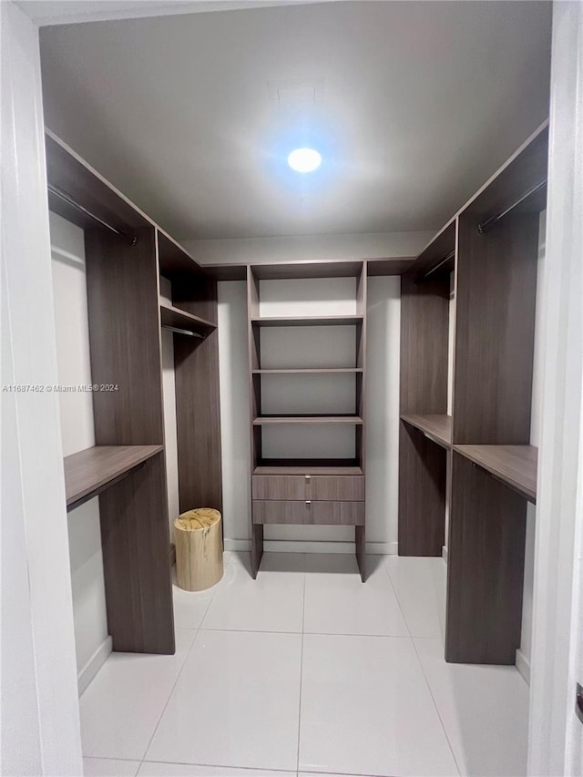 walk in closet with light tile patterned floors