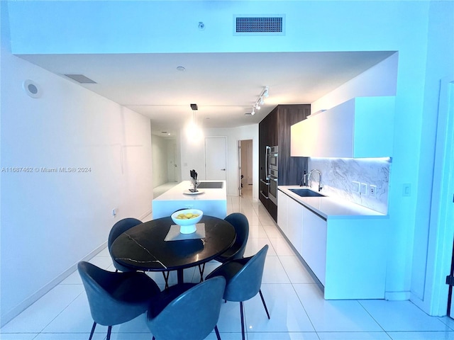 kitchen with white cabinets, decorative backsplash, sink, and light tile patterned flooring