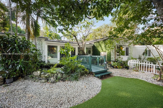 rear view of property with a wooden deck and a lawn