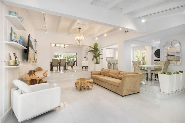 living room featuring track lighting, a chandelier, beamed ceiling, and stacked washer / dryer