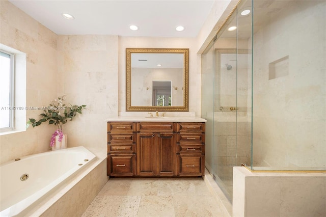 bathroom with independent shower and bath, vanity, a healthy amount of sunlight, and tile walls