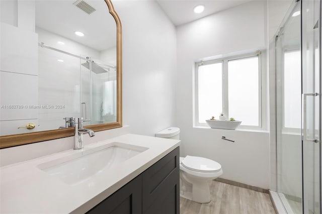 bathroom featuring vanity, toilet, a shower with door, and wood-type flooring