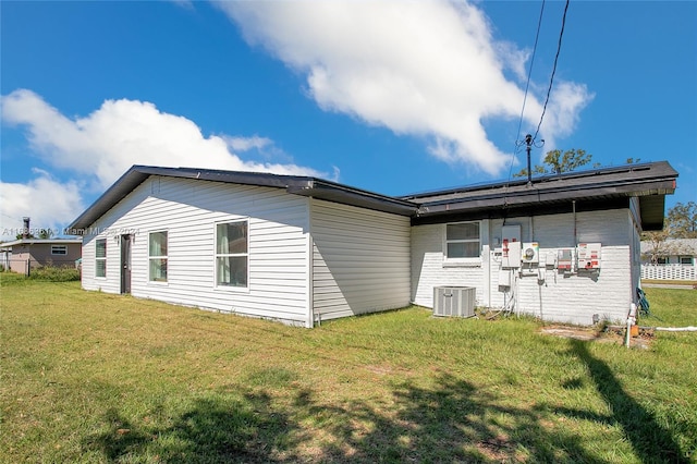 back of property featuring central AC and a lawn