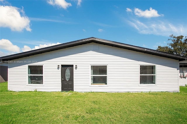 rear view of property featuring a lawn