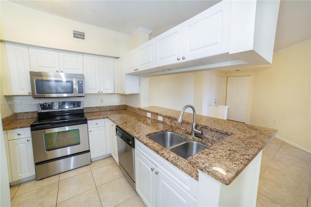 kitchen featuring light tile patterned floors, a peninsula, a sink, visible vents, and appliances with stainless steel finishes