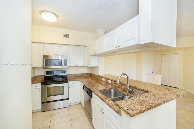 kitchen with kitchen peninsula, stainless steel appliances, sink, white cabinets, and a textured ceiling