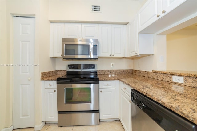 kitchen with appliances with stainless steel finishes, light stone counters, white cabinetry, and light tile patterned flooring