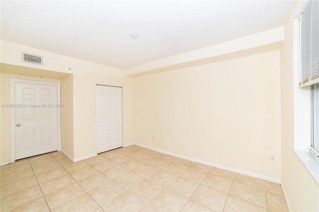 tiled spare room with a textured ceiling