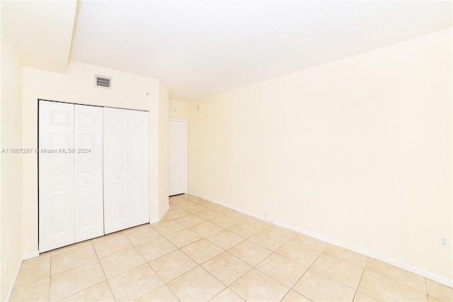 unfurnished bedroom with a textured ceiling, a closet, and light tile patterned floors