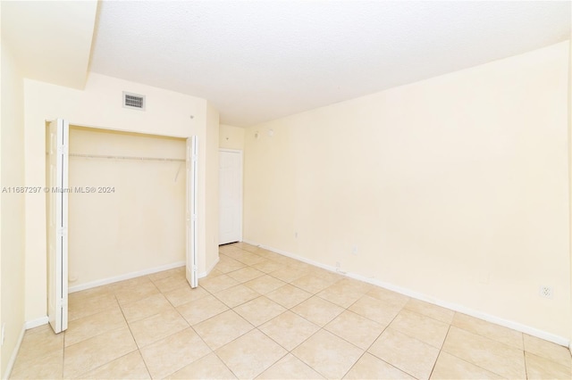 unfurnished bedroom featuring a closet, a textured ceiling, and light tile patterned floors