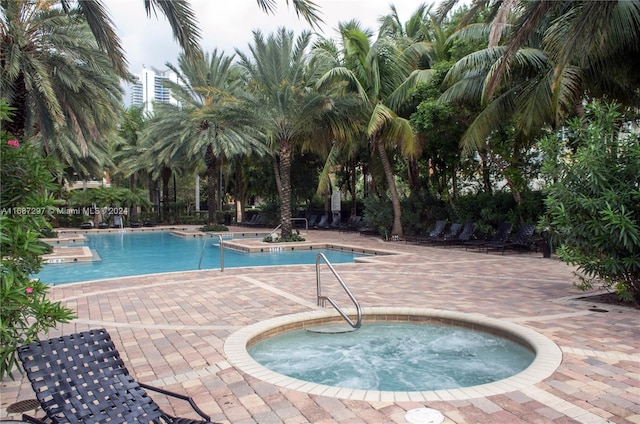 view of swimming pool featuring a patio and a hot tub